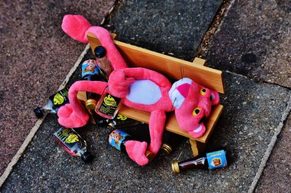 Drunk pink panther on bench surrounded by empties